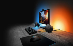 Gaming-Lautsprecher Logitech G506 auf einem Schreibtisch mit Monitor und stimmungsvollem Licht.