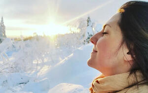 Julia Siefert Winter in winterlicher Schneelandschaft: Sie atmet tief ein - mit geschlossenen Augen genießt sie die kalte Winterluft, während sie das letzte Lichtd er untergehenden Sonne über ihr Gesicht streift