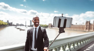 Mann fotografiert sich mit Selfie Stick