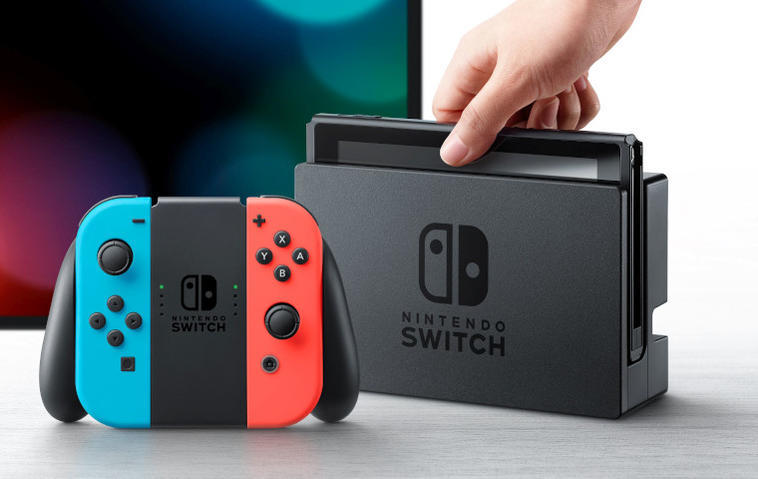 Eine Nintendo Switch wird von einer Hand aus dem TV-Dock gehoben. Im Vordergrund sind Joy-Con-Controller zu sehen, im Hintergrund ein Fernseher.