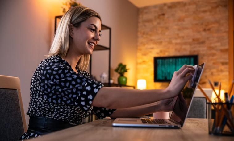 Frau, die den Bildschirm eines Laptops reinigt