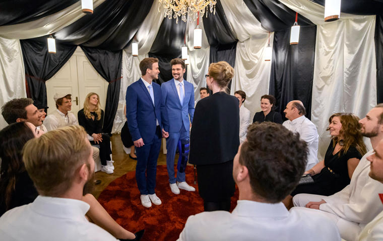 umringt von Hochzeitsgästen geben sich Boris (Florian Frowein, l.) und Tobias (Max Beier, M.) vor Standesbeamtin Antonia Wiener (Stefanie Oestreich, r.) das Ja-Wort.